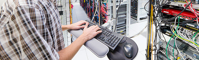 technician-looking-at-camera-working-on-computer-in-server-room-of-efx0yn